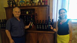 Un homme et une femme se tiennent devant un meuble à vin en bois rempli de bouteilles de vin.