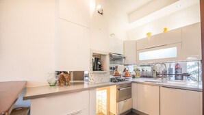 Una cocina moderna con armarios blancos, horno empotrado, estufa y lavamanos.