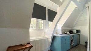Une cuisine de taille réduite, dotée d’une fenêtre, d’un lave-linge et d’un four à micro-ondes.