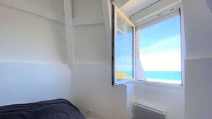 Une chambre à coucher avec un lit, une fenêtre donnant sur la mer et un radiateur.