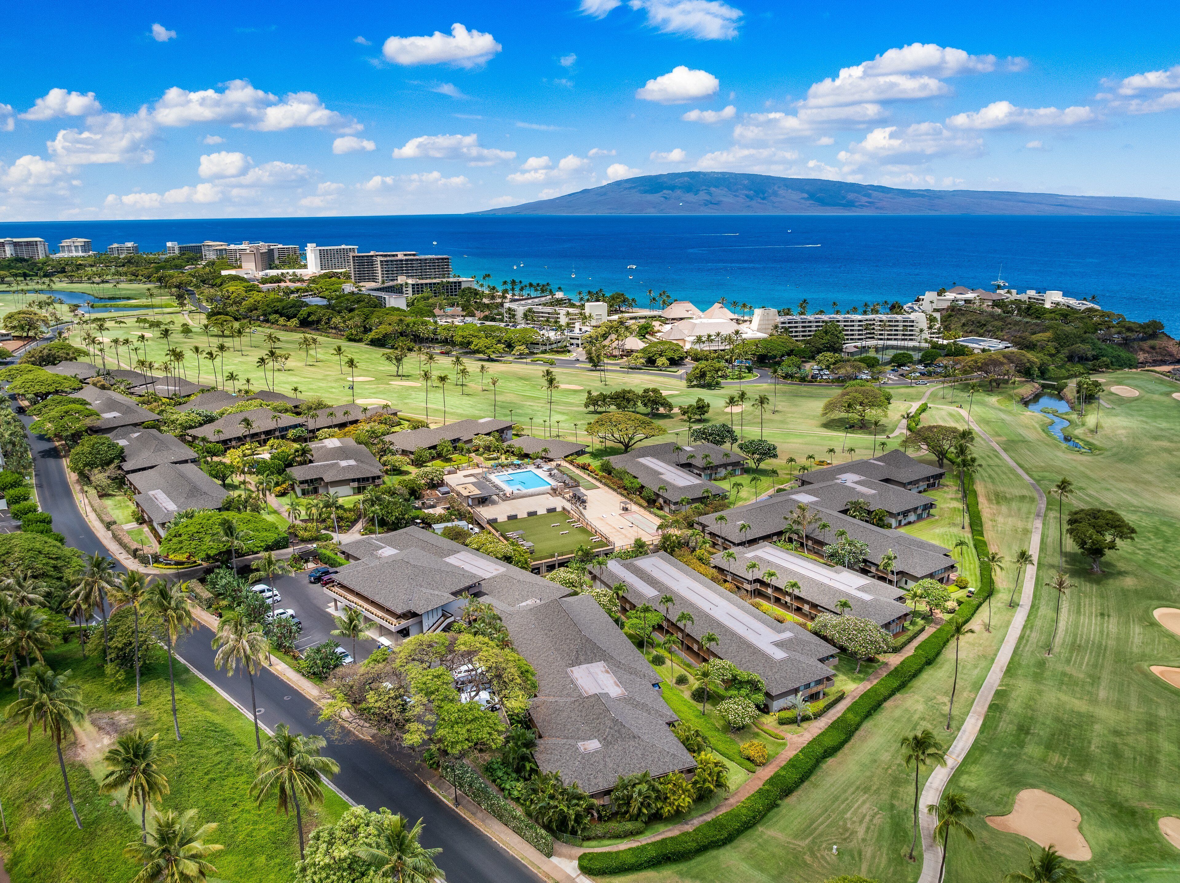 A resort with multiple bungalow-style buildings, a central pool, and a golf course.