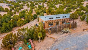 Edifici rústic amb teulada metàl·lica i parets de fusta, envoltat d'un paisatge desert amb vegetació escassa i muntanyes llunyanes.