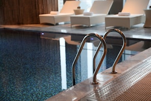 A pool area with metal handrails and lounge chairs with cushions. - Crowne Plaza Nanning City Center by IHG (Nanning)