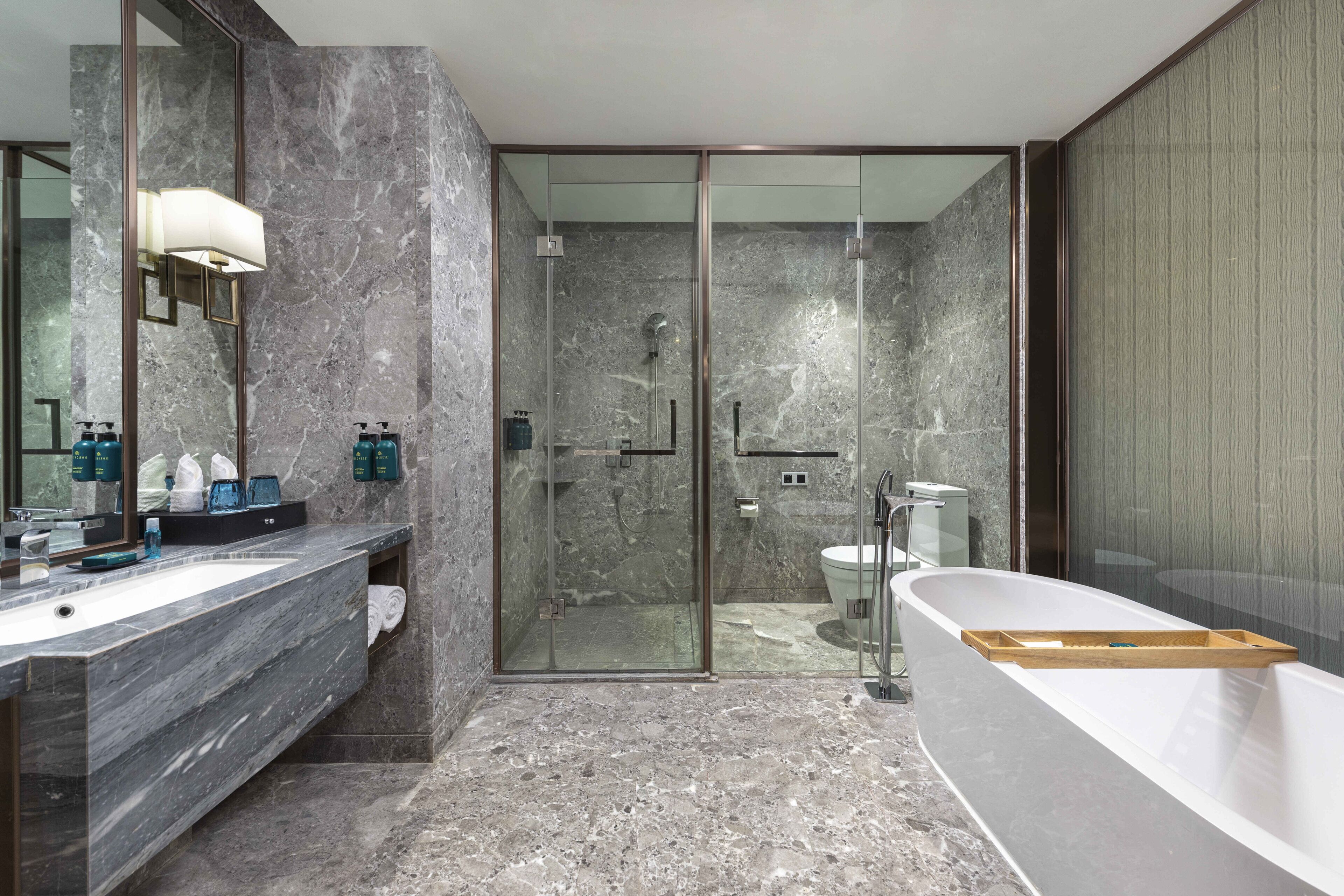Un baño moderno con encimera de mármol, ducha con mampara de cristal y bañera independiente.