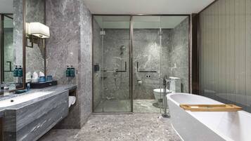 A modern bathroom with a marble countertop, a glass-enclosed shower, and a freestanding bathtub.