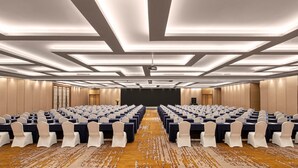 Un salón de conferencias con mesas, sillas y una pantalla de proyector.