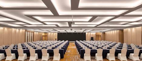 A conference room with rows of tables, chairs, and a projector screen.