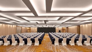 Un salón de conferencias con mesas, sillas y una pantalla de proyector.