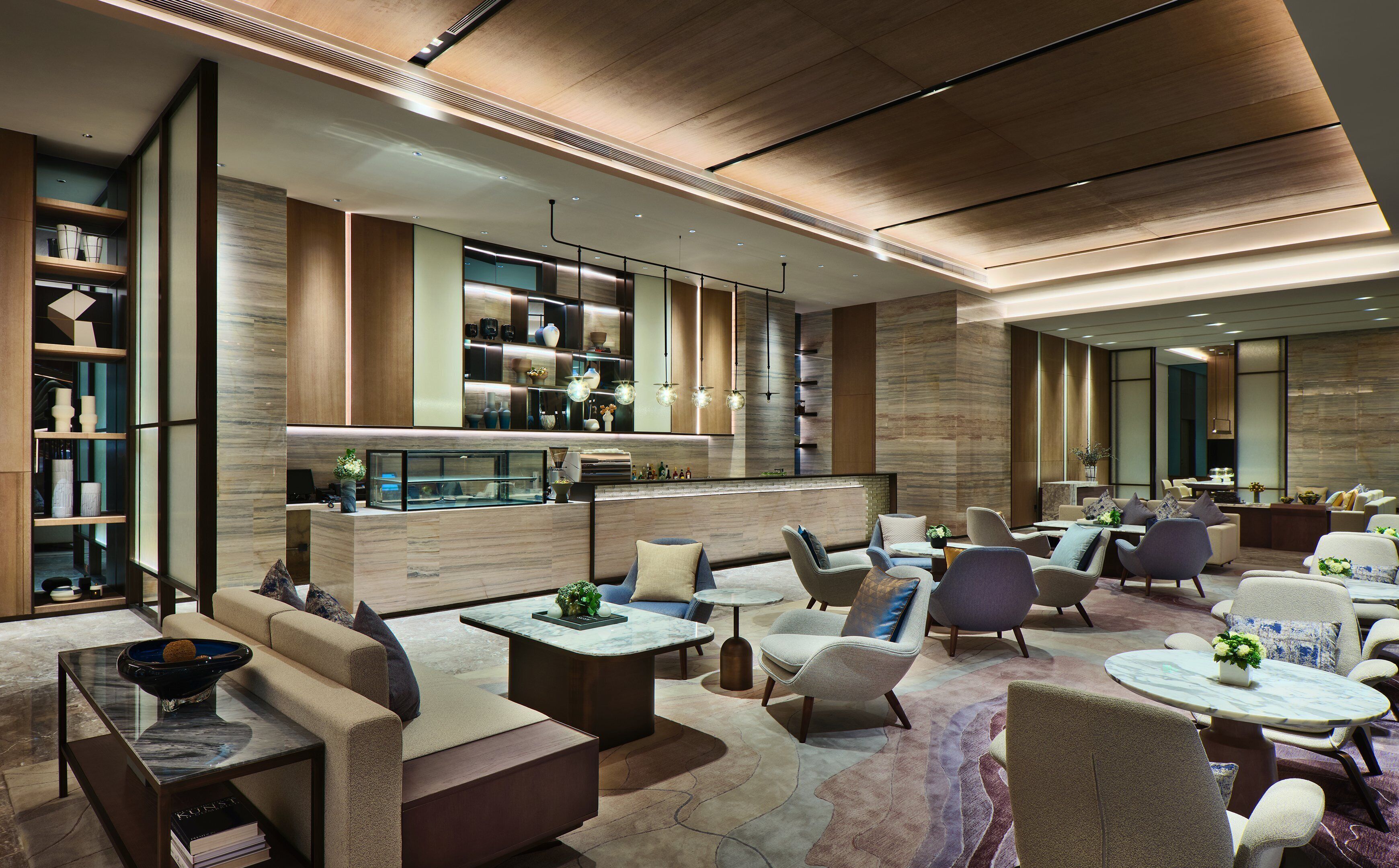 Eine moderne Hotelhalle mit einer Rezeption, einer Sitzecke und einer Bar.