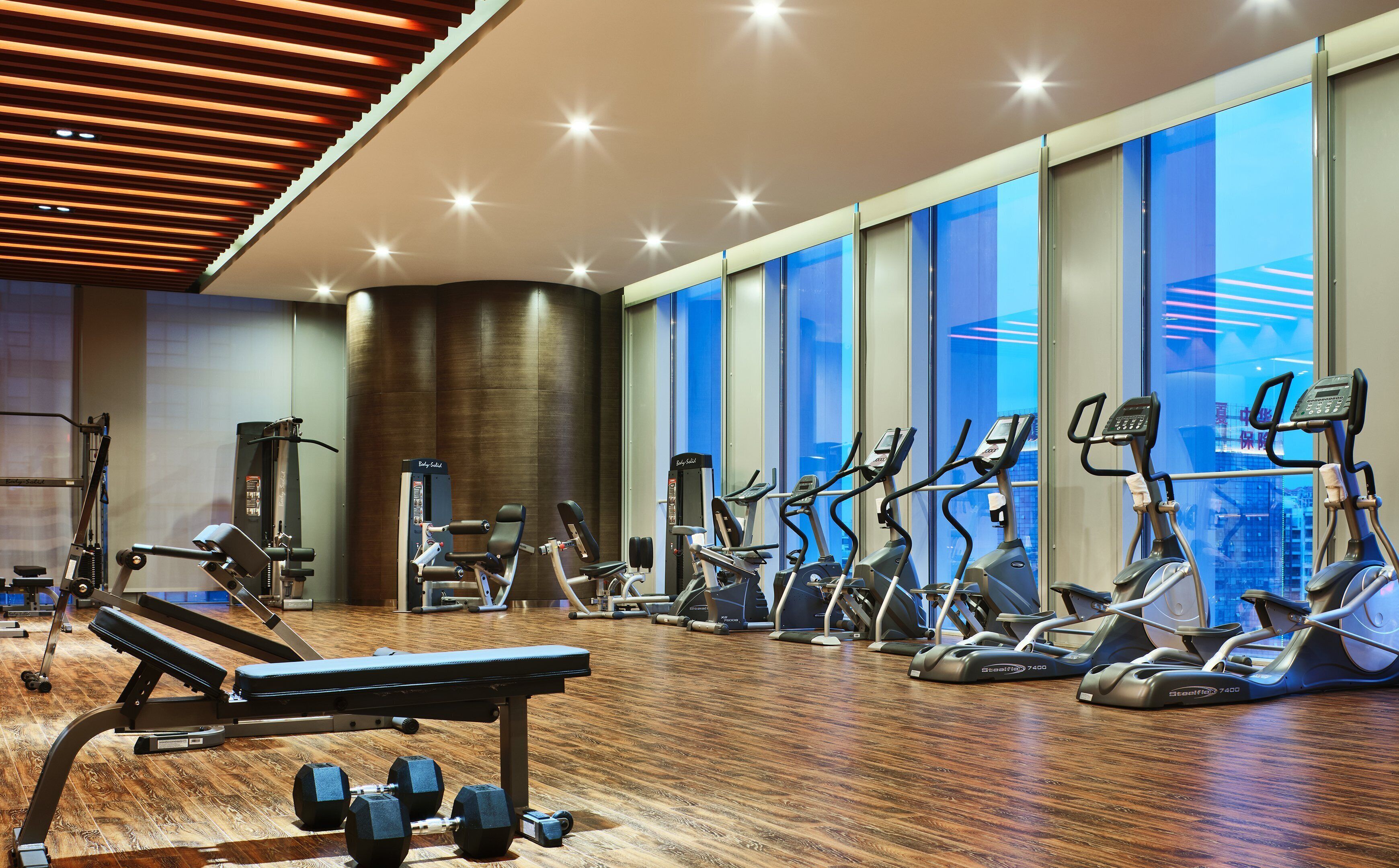 A gym with exercise equipment, a bench, and dumbbells.