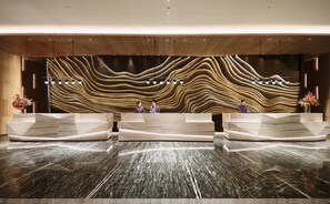 Un espace d'accueil au design moderne, caractéris é par un motif mural ondulé original et des comptoirs d'accueil en marbre.