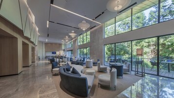 Un vestíbulo amplio con mobiliario moderno, ventanas grandes y vistas al exterior.