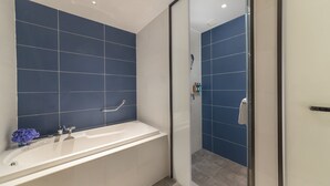 A bathroom with a bathtub, a glass shower enclosure, and a handrail. - Holiday Inn Express E'Mei Qiliping by IHG (Meishan)