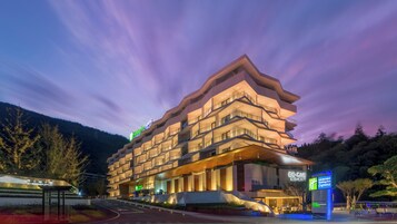 Un hotel de varios pisos con un diseño arquitectónico moderno, que cuenta con balcones y una entrada destacada.