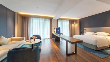 Una habitación de hotel con una cama, un escritorio, una silla, un sofá y una mesa de centro.