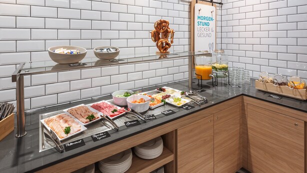 A buffet setup with various food items and a sign indicating 'Moregen-Studen-Lecker & Gesund'.