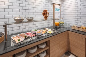 Buffet com diversos alimentos e placa indicando 'Moregen-Studen-Lecker & Gesund'.