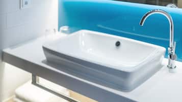 A modern bathroom with a white sink, chrome faucet, and a blue accent wall.