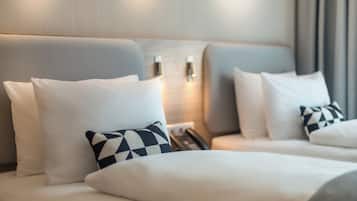 A hotel room with two beds, white bedding, and a checkered pillow.