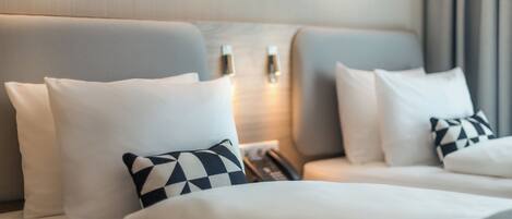A hotel room with two beds, white bedding, and a checkered pillow.