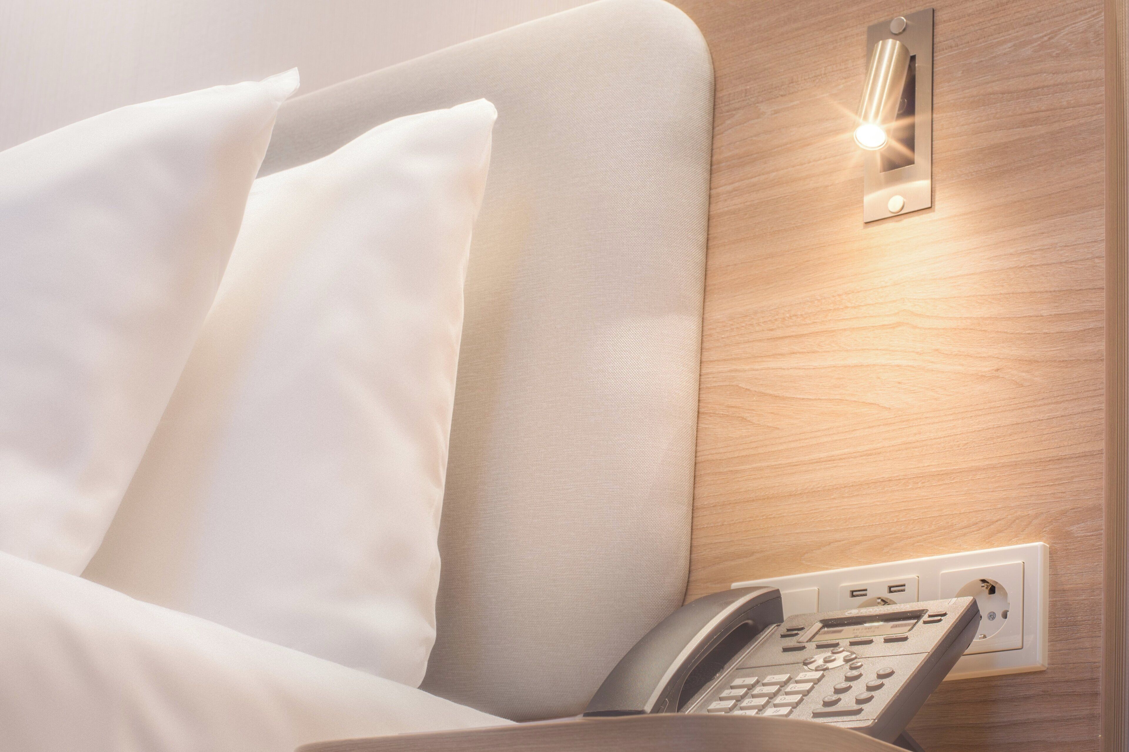 Una habitación de hotel con una cama, un teléfono en la pared y un accesorio de iluminación.