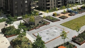 Un moderno conjunto residencial con varios edificios, zona de estacionamiento y jardines ajardinados.