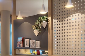 Un intérieur moderne agrémenté de luminaires suspendus, d’une plante fixée au mur et d’œuvres d’art encadrées.