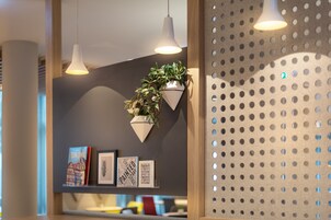Um interior moderno com iluminação pendente, planta suspensa na parede e obras de arte emolduradas.