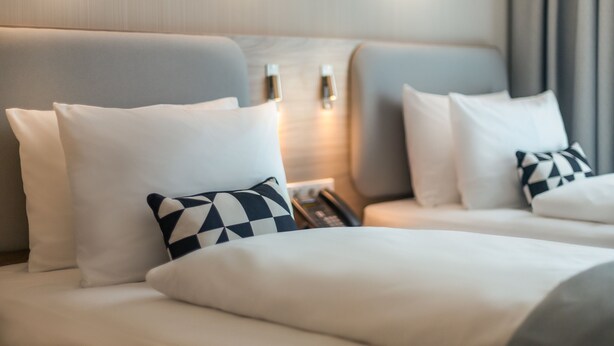 Una habitación de hotel con una cama grande, dos mesitas de noche y un buró con un teléfono.