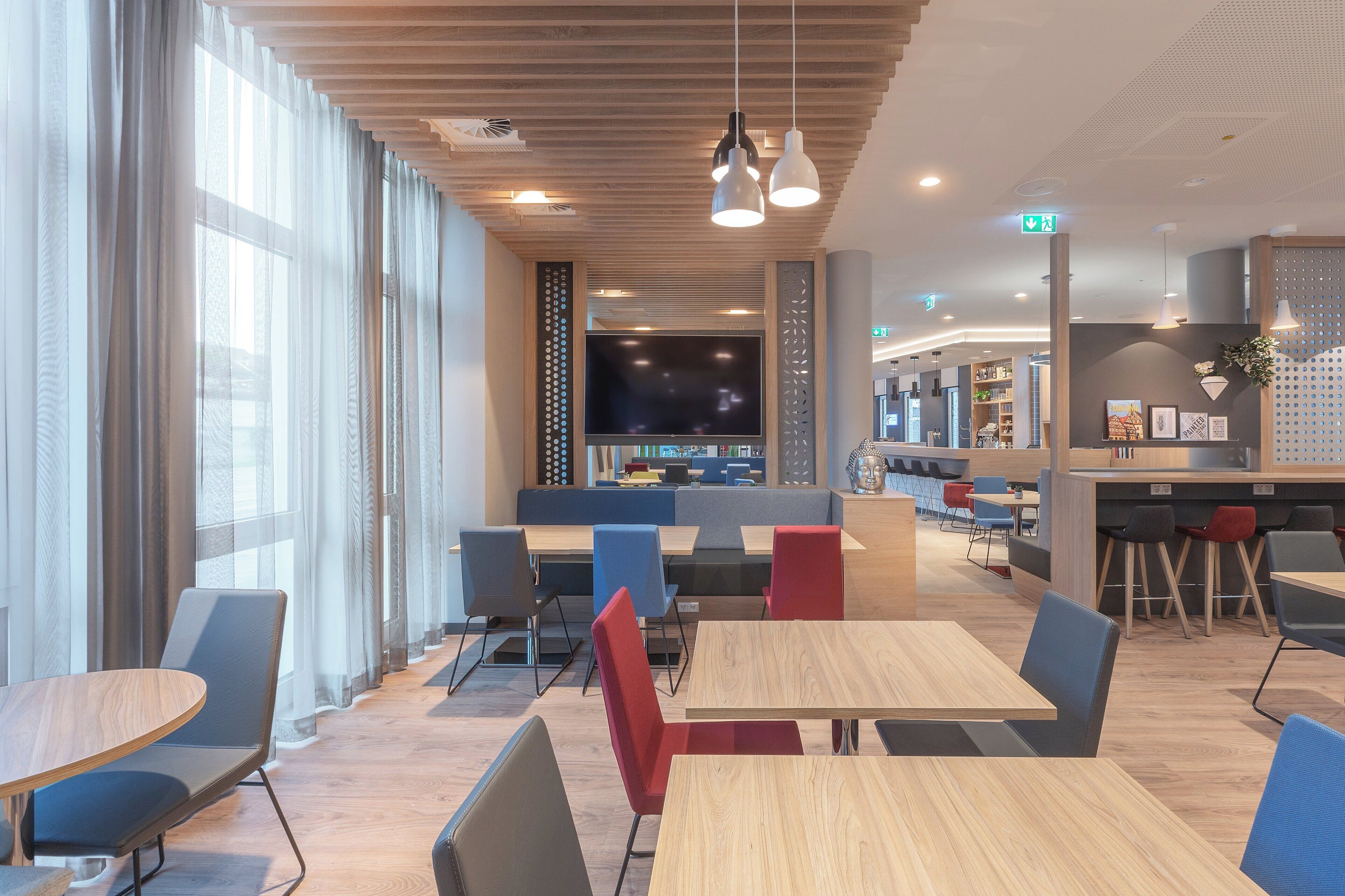 A modern interior with seating areas, a bar, and a large flat-screen TV.