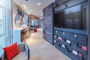 A modern interior with a long corridor, seating areas, and a large wall-mounted screen. - Holiday Inn Express Erlangen by IHG (Erlangen)
