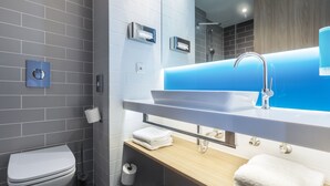Un baño moderno con inodoro blanco, lavamanos y pared de acento azul, y espejo sobre el lavamanos.