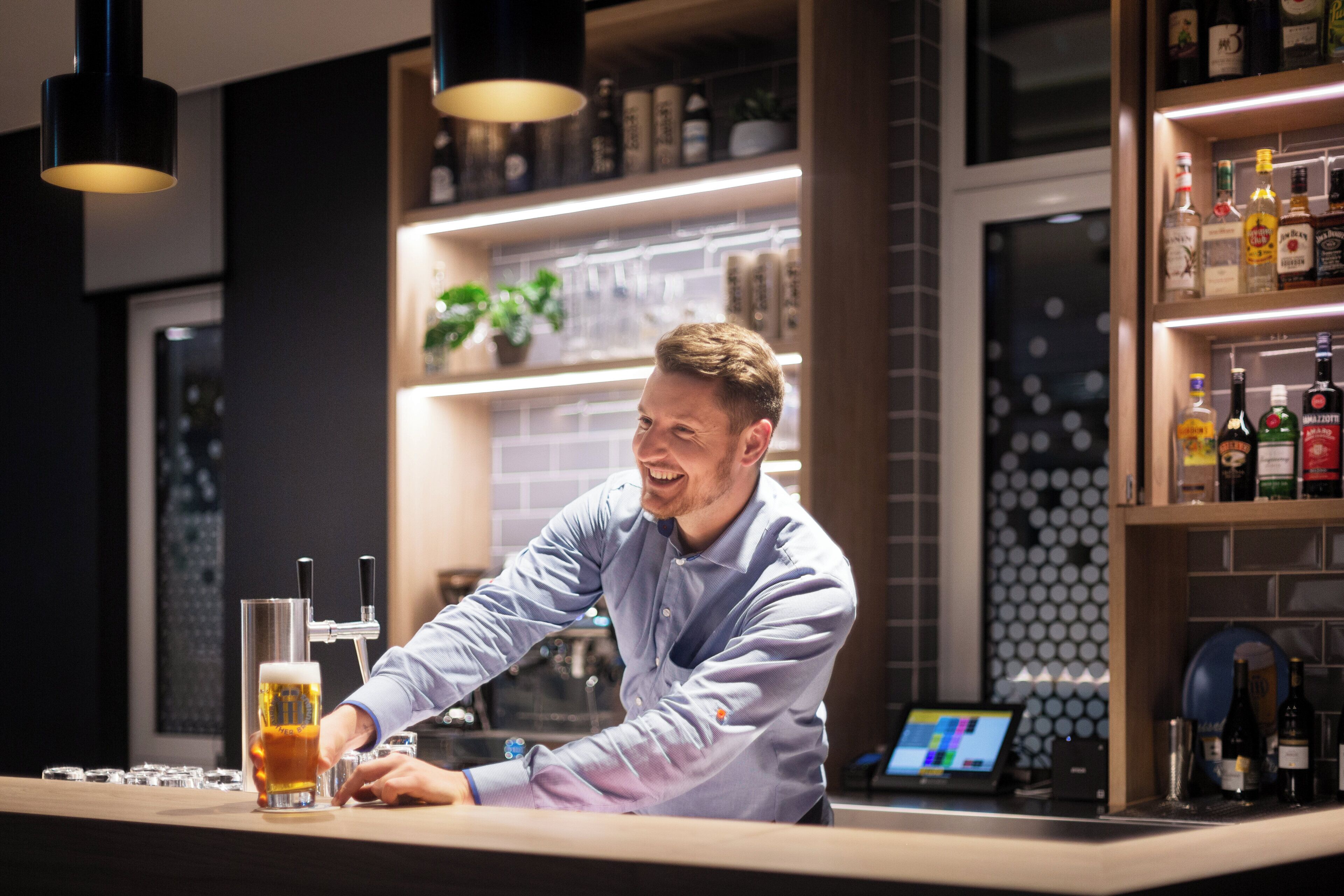 A bar area with a bartender, a beer tap, and shelves with bottles.