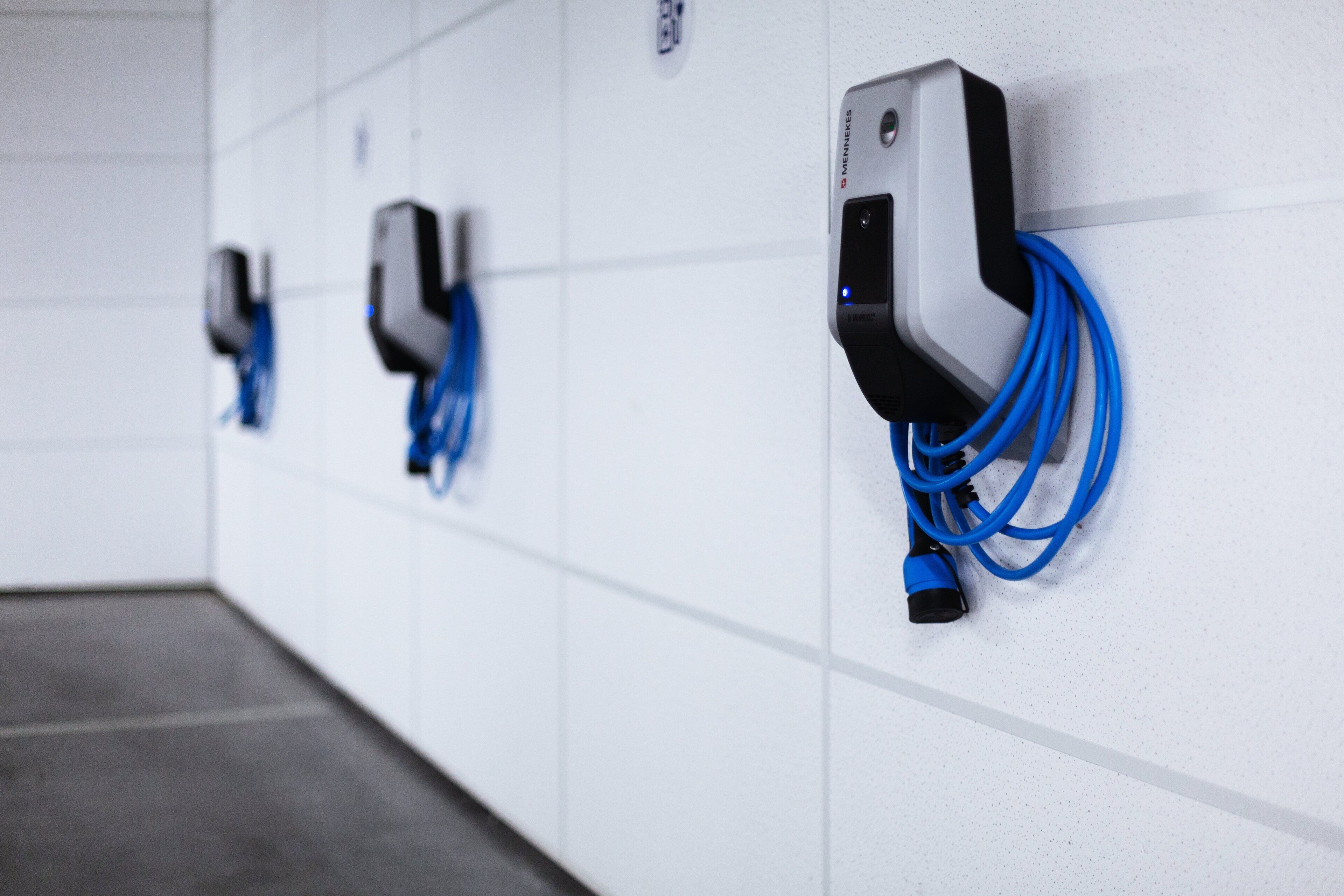 A row of electric vehicle charging stations mounted on a white wall in a clean, modern indoor setting.