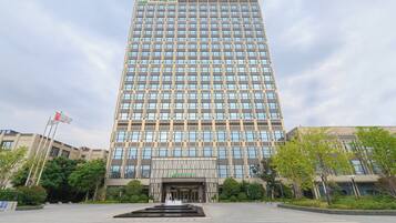 Un edificio alto y moderno con un letrero de Holiday Inn, que presenta una entrada amplia con una fuente ornamental al frente.