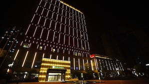 A modern hotel with a prominent vertical light design and a well-lit entrance. - Holiday Inn Kunshan by IHG (Suzhou)