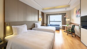 A hotel room with two beds, a desk with a lamp, a chair, a TV, and a window with a view. - Holiday Inn Kunshan by IHG (Suzhou)