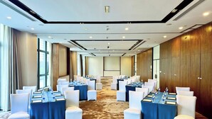 Una sala conferenze con tavoli e sedie, ampie finestre e pavimento in moquette.