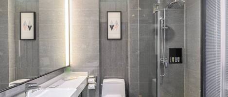 Een moderne badkamer met een douchecabine van glas, een wit wastafelmeubel en een toilet.