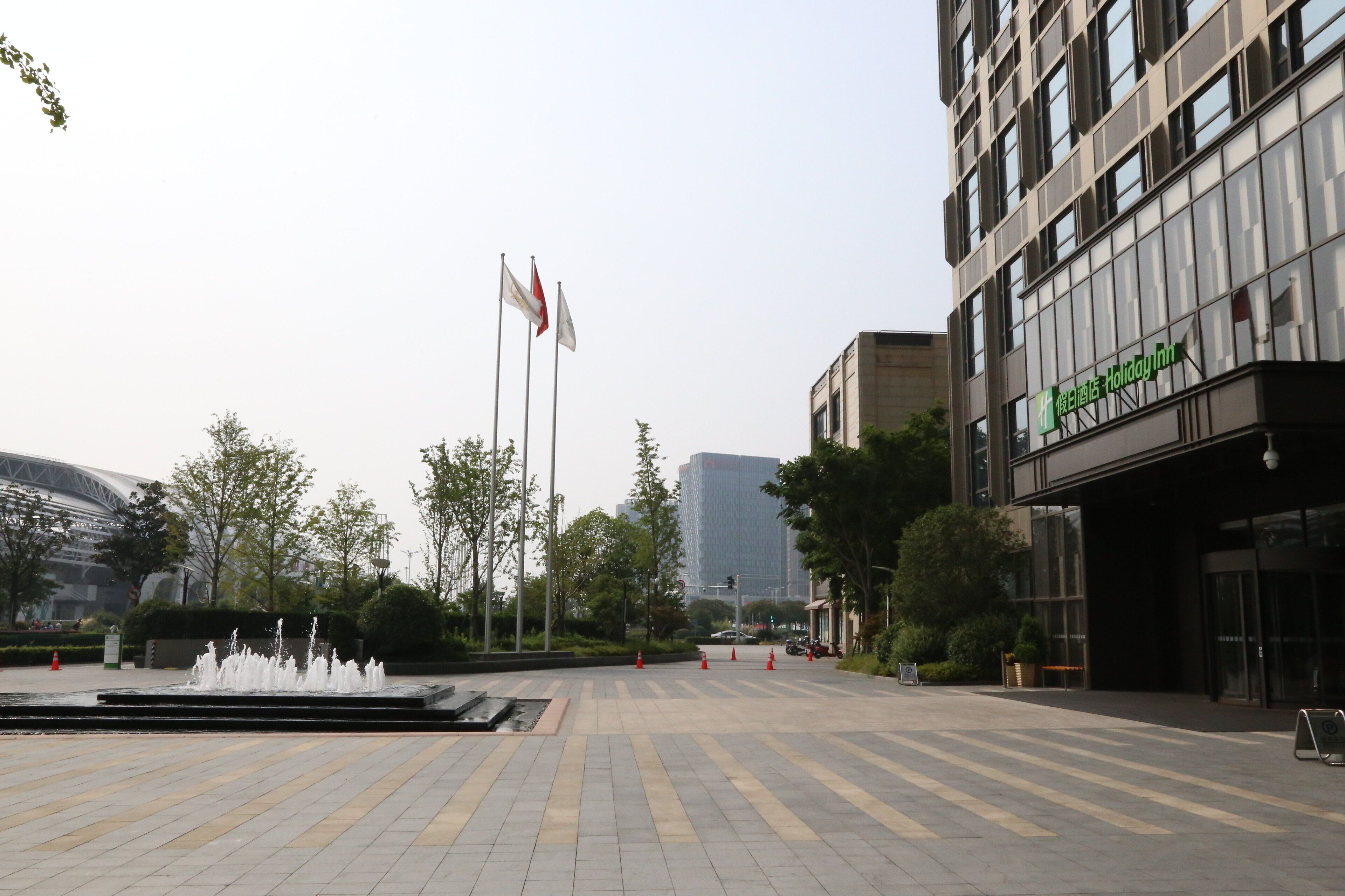 A hotel entrance with a fountain, flags, and modern buildings in the background.