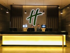 Una recepción con un gran logotipo iluminado, dos monitores y una pantalla digital.