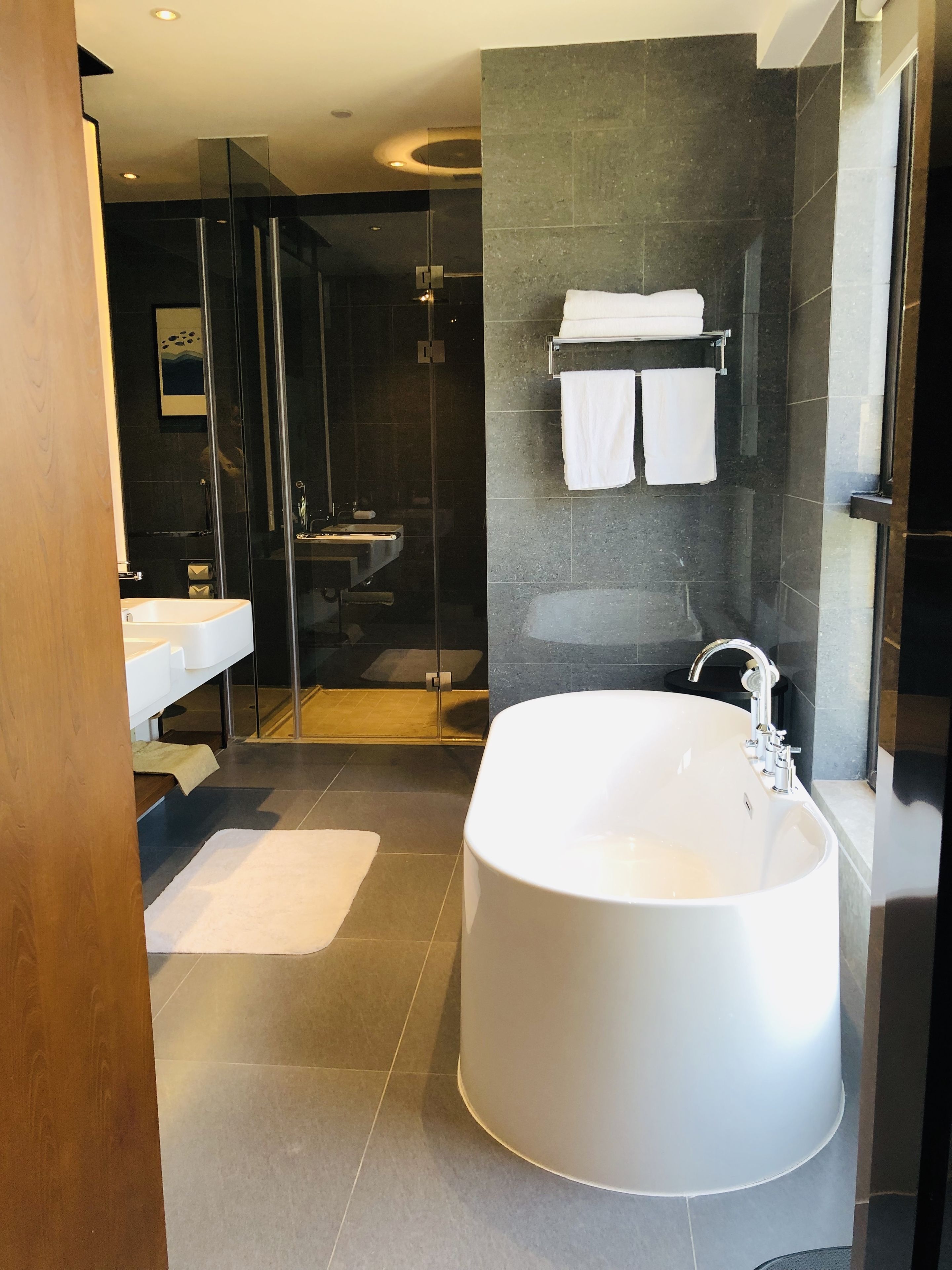 A modern bathroom with a freestanding bathtub, a glass-enclosed shower, and a vanity with a mirror.