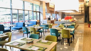 A modern restaurant with large windows, multiple seating areas, and a central counter. - Holiday Inn Kunshan by IHG (Suzhou)