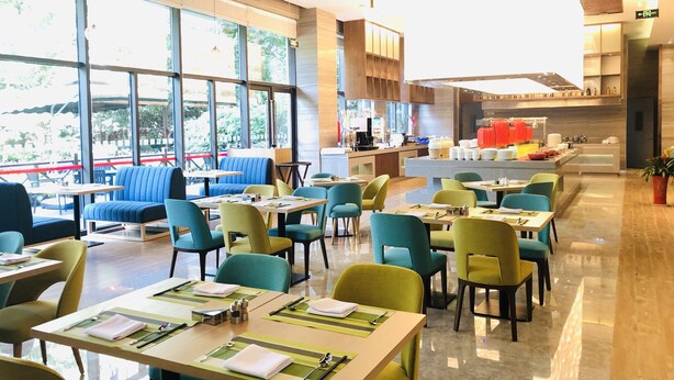 Un ristorante moderno con ampie vetrate, diverse zone di seduta e un bancone centrale.