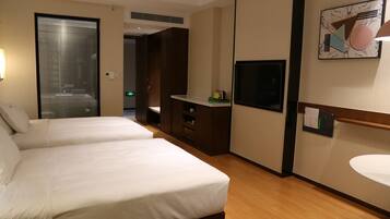 Habitación de hotel con dos camas, un escritorio, televisión y baño.