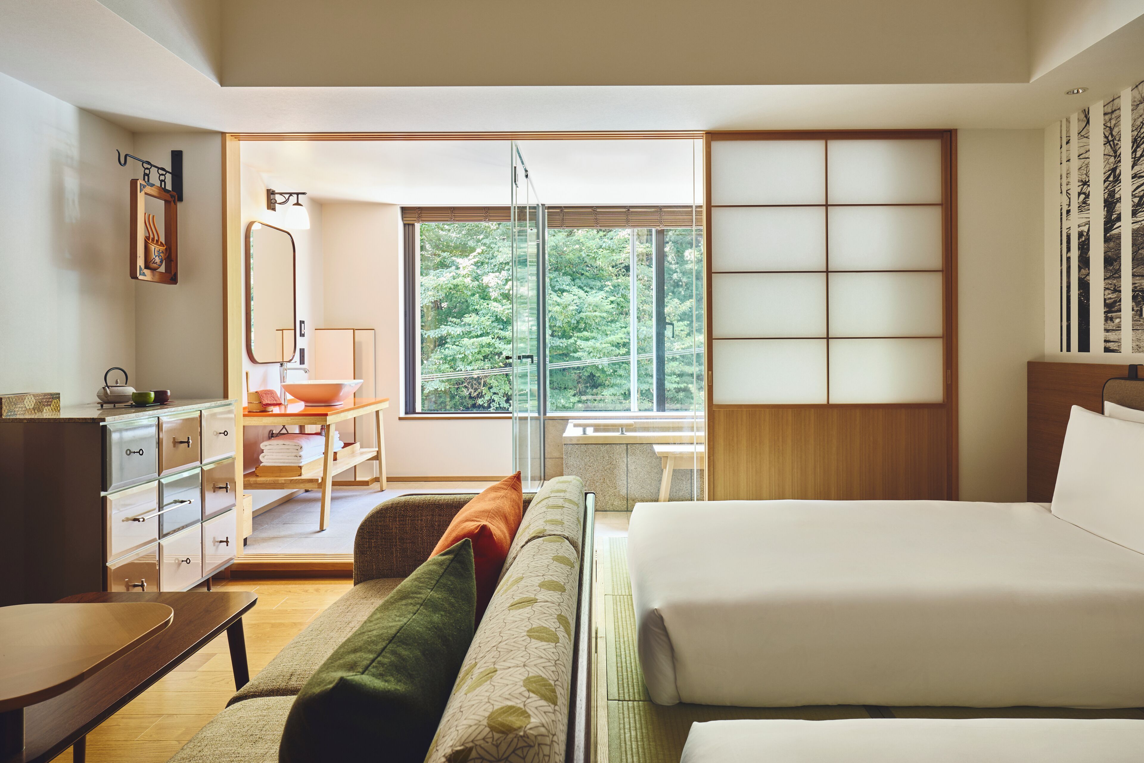 Une chambre moderne avec un grand lit, un bureau et une vue sur la verdure.