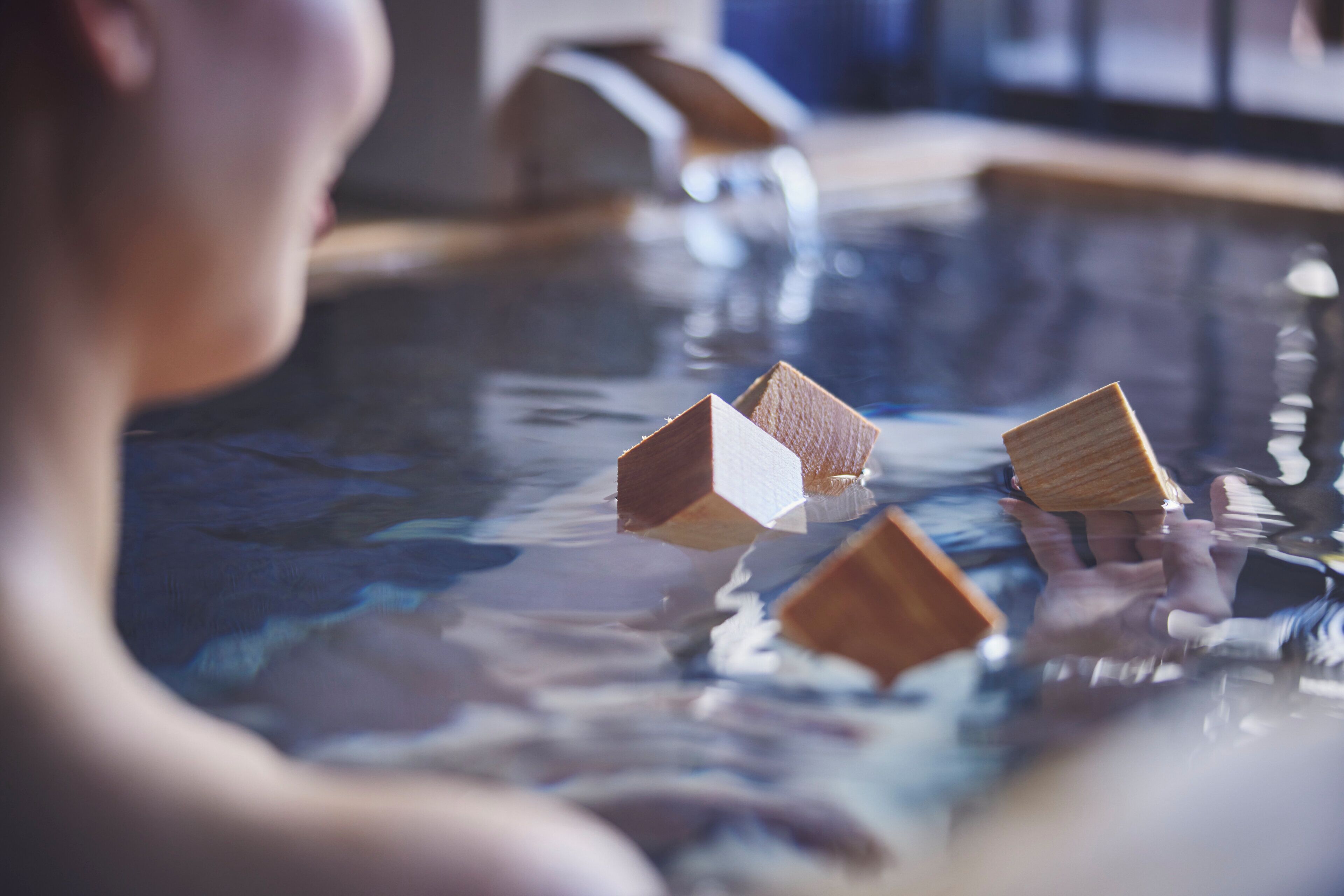 A person in a swimming pool with wooden blocks floating on the water.