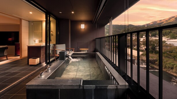 Un moderno espacio de spa con hidromasaje, asientos y vistas a un río y montañas.