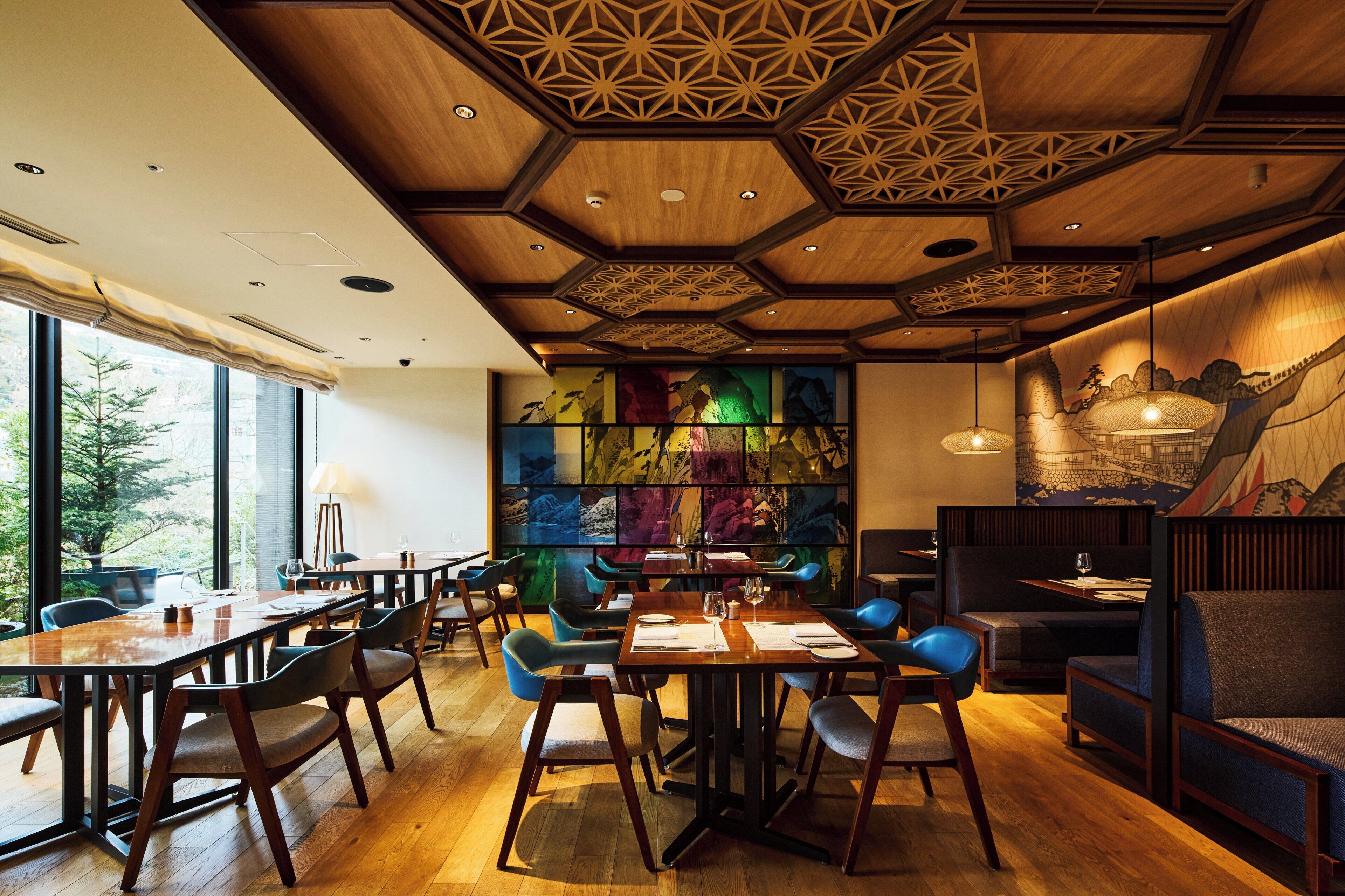 A restaurant with wooden ceiling, large windows, and colorful artwork on the wall.