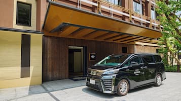 Een zwarte SUV geparkeerd voor een gebouw met een houten gevel en een bord waarop 'HOTEL INDIGO' staat.
